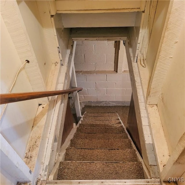 stairway featuring concrete block wall