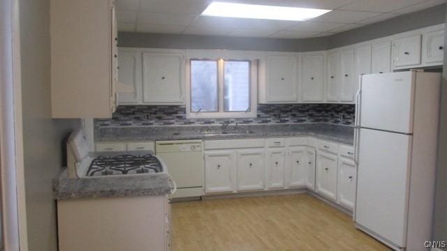 kitchen with white cabinetry, sink, a drop ceiling, and white appliances