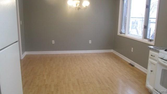 unfurnished dining area with a chandelier and light hardwood / wood-style floors