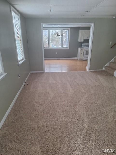 unfurnished living room with light carpet and a notable chandelier