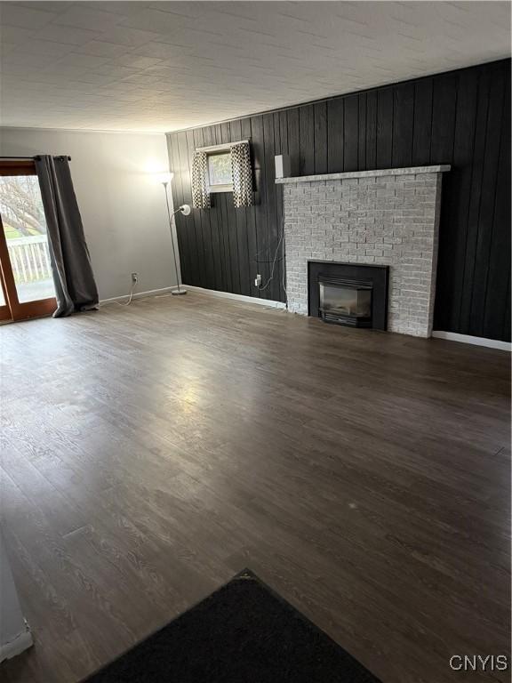 unfurnished living room featuring hardwood / wood-style floors, a fireplace, and wooden walls