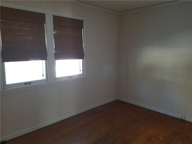 empty room featuring dark wood-type flooring and ornamental molding