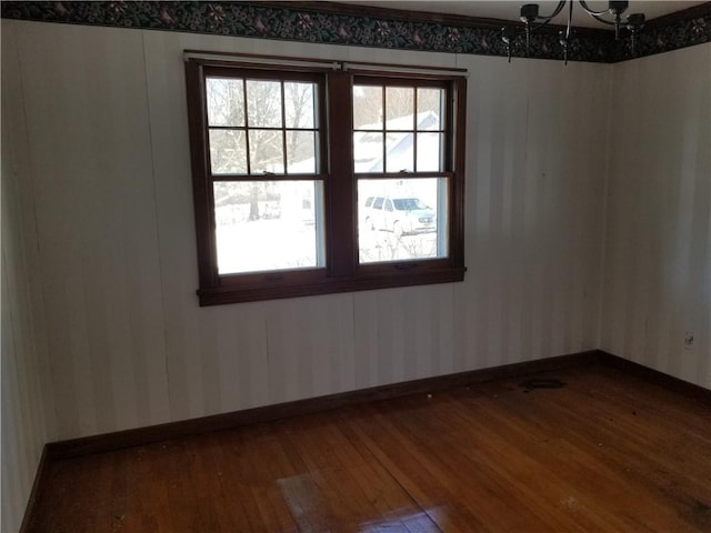 empty room featuring a chandelier and wood-type flooring