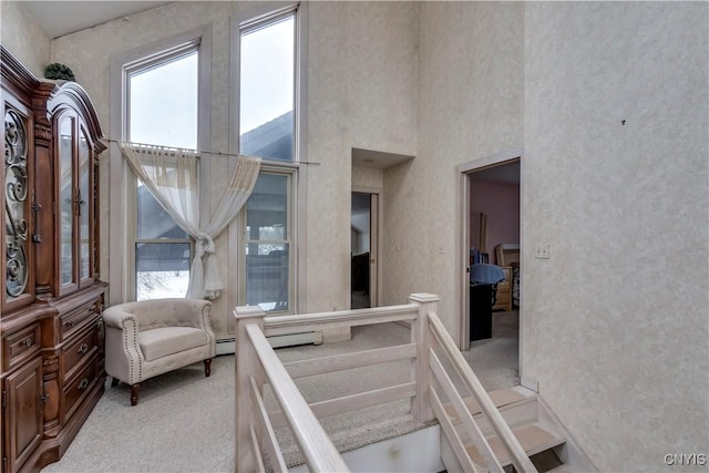 interior space with a towering ceiling, carpet floors, and a baseboard radiator