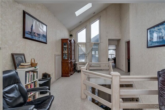 interior space with a skylight, light carpet, and high vaulted ceiling