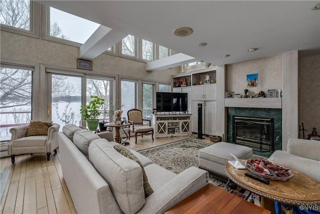 living room with hardwood / wood-style flooring, a premium fireplace, and a high ceiling