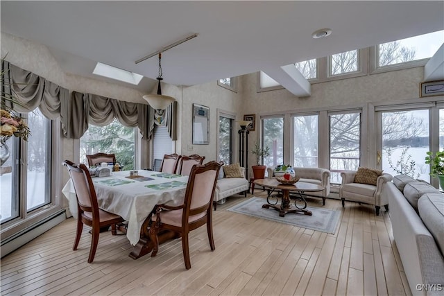 dining space with light hardwood / wood-style floors, a skylight, and a baseboard radiator