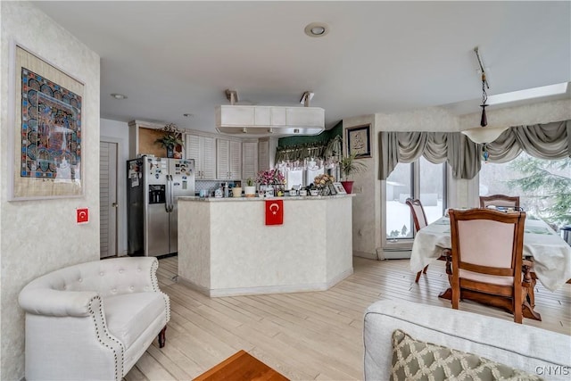 kitchen featuring stainless steel fridge, light wood-type flooring, white cabinetry, and a baseboard radiator