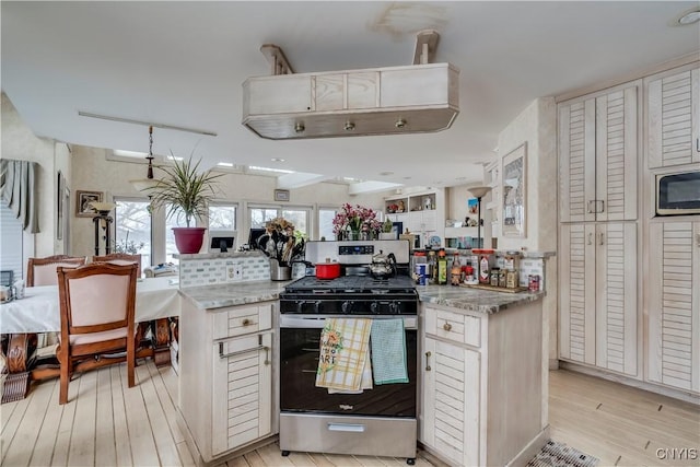 kitchen with rail lighting, stainless steel gas stove, light stone countertops, light wood-type flooring, and white cabinetry