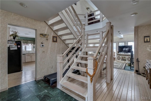 stairway with a wealth of natural light, sink, and wood-type flooring