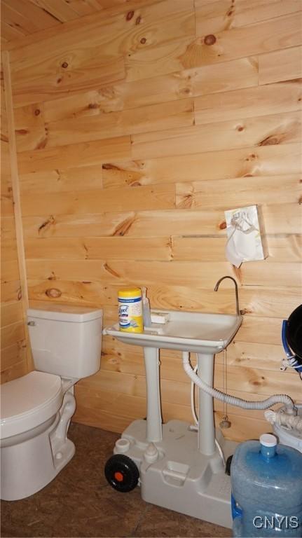 bathroom featuring toilet and wooden walls