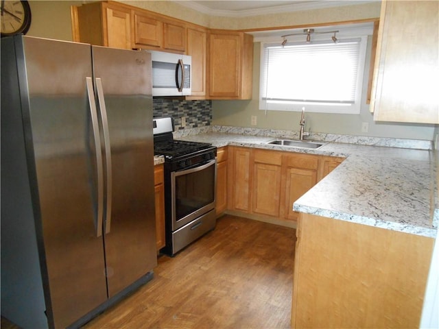 kitchen featuring light stone countertops, sink, tasteful backsplash, light hardwood / wood-style floors, and appliances with stainless steel finishes