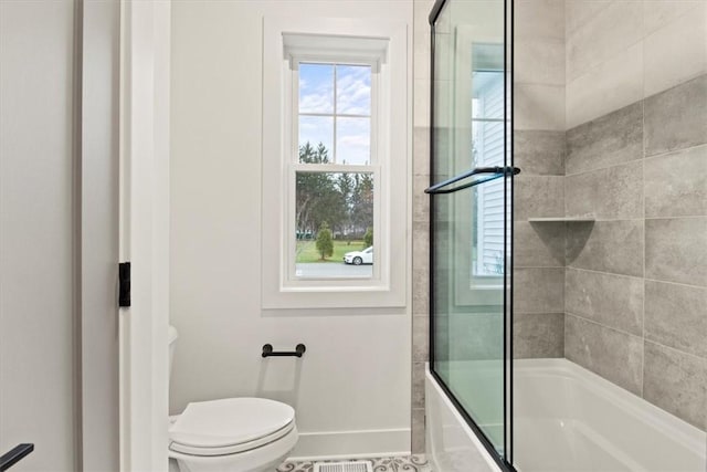 bathroom featuring enclosed tub / shower combo and toilet