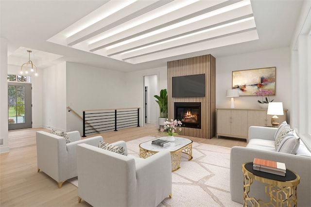 living room featuring a notable chandelier, a fireplace, and light hardwood / wood-style flooring