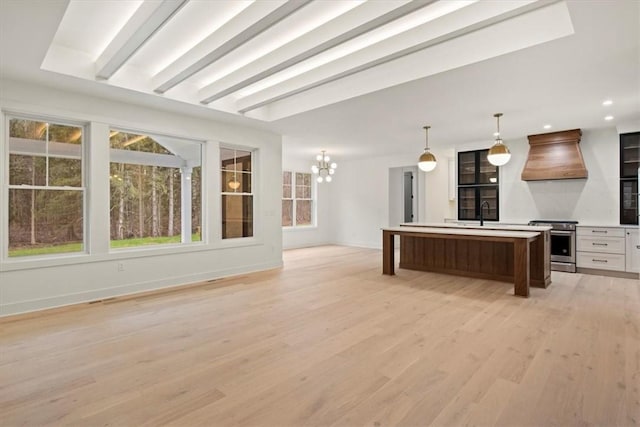 kitchen with premium range hood, pendant lighting, an inviting chandelier, a center island, and stainless steel stove