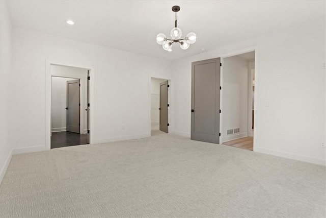 unfurnished room with carpet floors and a chandelier