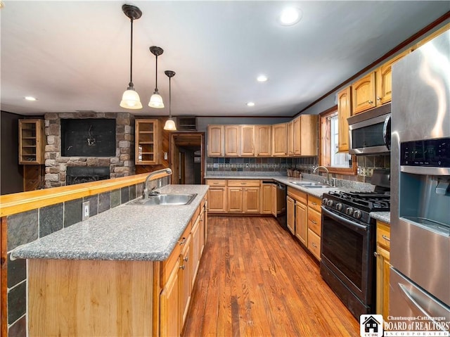 kitchen with decorative backsplash, sink, black appliances, a fireplace, and a kitchen island