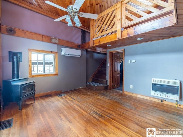 unfurnished living room with wooden ceiling, a wood stove, ceiling fan, a wall mounted AC, and heating unit