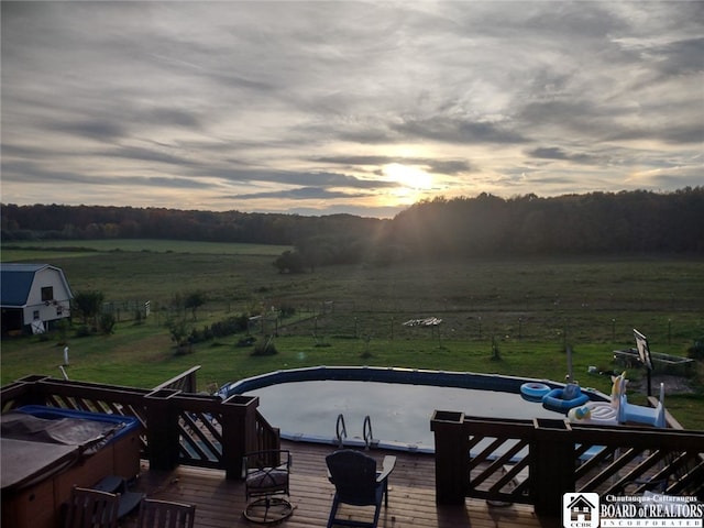 pool at dusk with a rural view and a deck