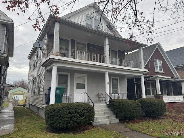 view of front of property featuring covered porch, a garage, an outbuilding, and a balcony