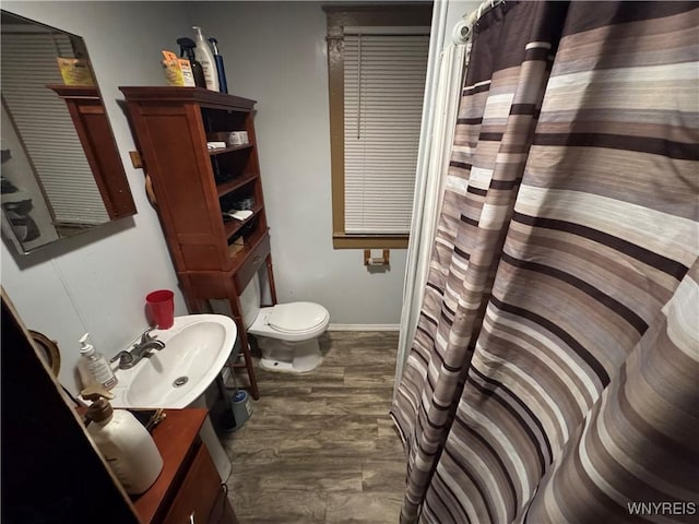 bathroom with wood-type flooring, toilet, and sink