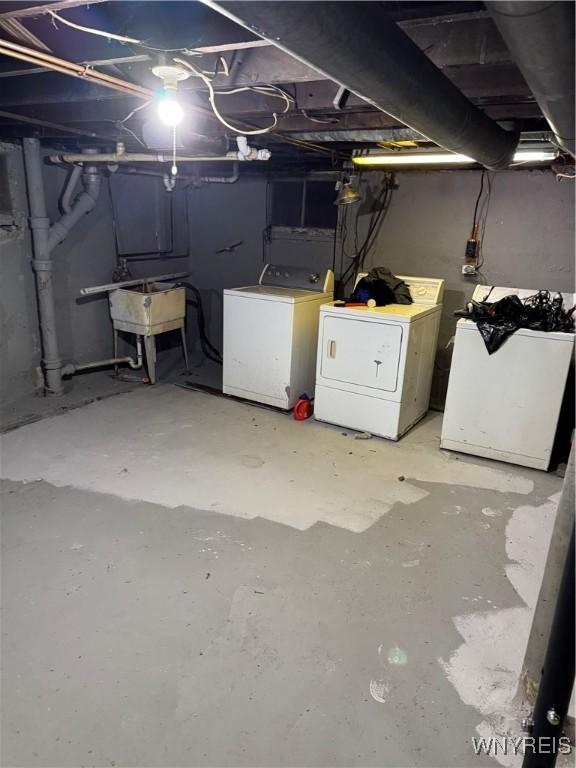 basement featuring refrigerator, washer and clothes dryer, and sink