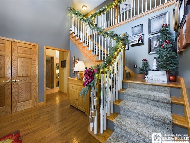 stairs with hardwood / wood-style flooring and a towering ceiling