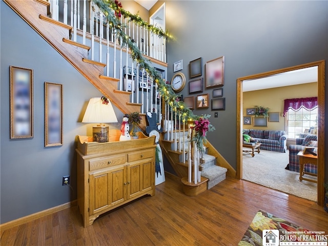 stairs featuring a high ceiling and hardwood / wood-style flooring