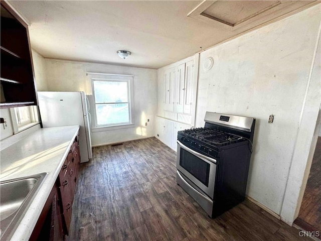 kitchen with white refrigerator, stainless steel gas stove, dark wood-type flooring, and sink