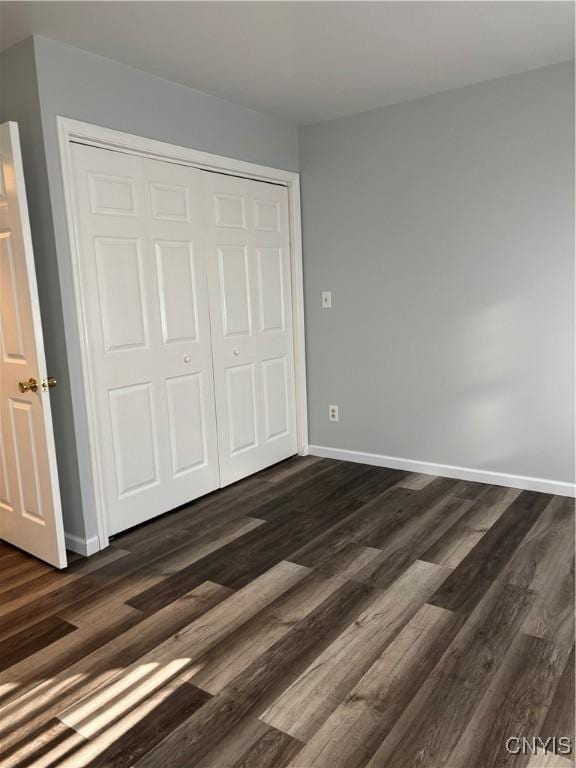 unfurnished bedroom featuring dark hardwood / wood-style flooring and a closet