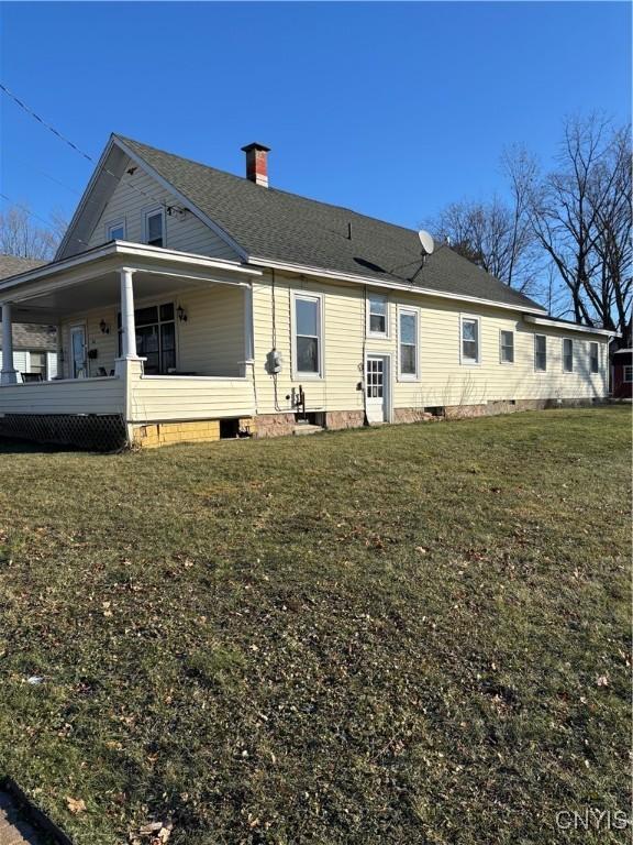 rear view of house with a porch and a lawn