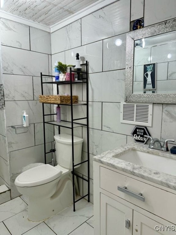 bathroom with vanity, toilet, and tile walls