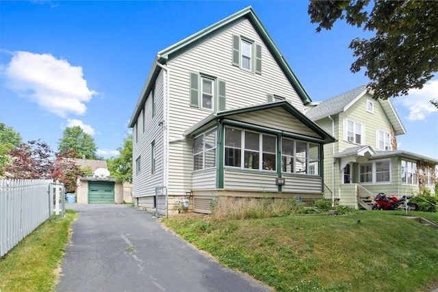 front of property with a sunroom, an outbuilding, a front lawn, and a garage