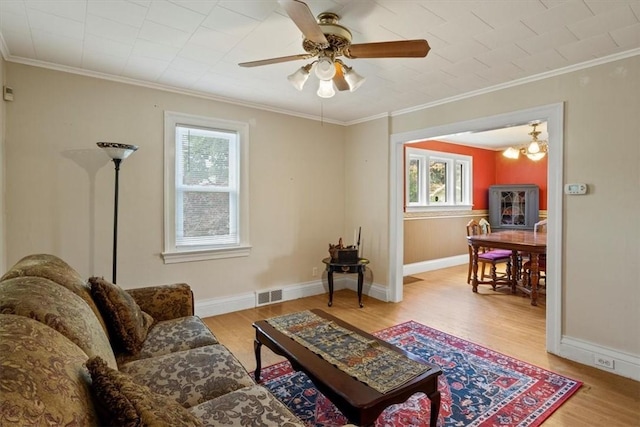 living room with ceiling fan with notable chandelier, light hardwood / wood-style floors, and crown molding