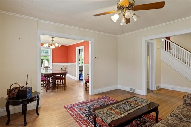 living room with hardwood / wood-style flooring, ceiling fan with notable chandelier, and ornamental molding