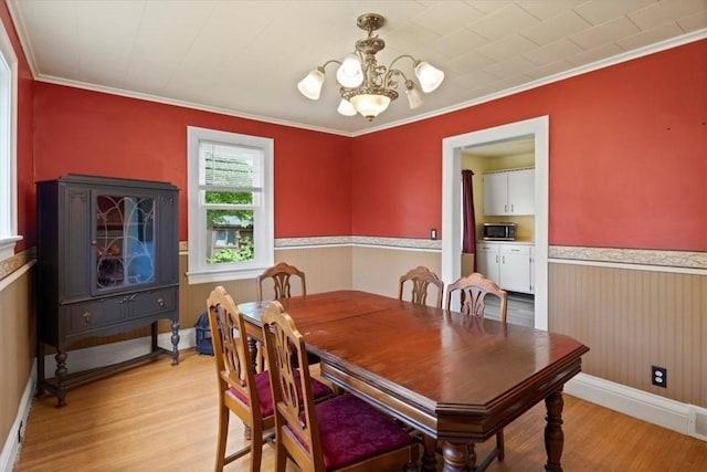 dining space with light hardwood / wood-style floors, a notable chandelier, and ornamental molding