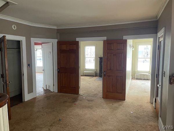 hall with light carpet, radiator, and crown molding