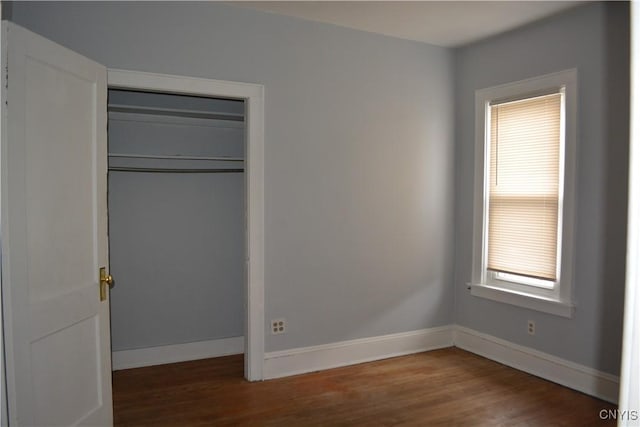 unfurnished bedroom featuring a closet and dark wood-type flooring