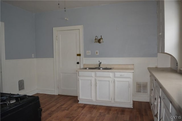 kitchen with dark hardwood / wood-style flooring, white cabinetry, sink, and black range oven