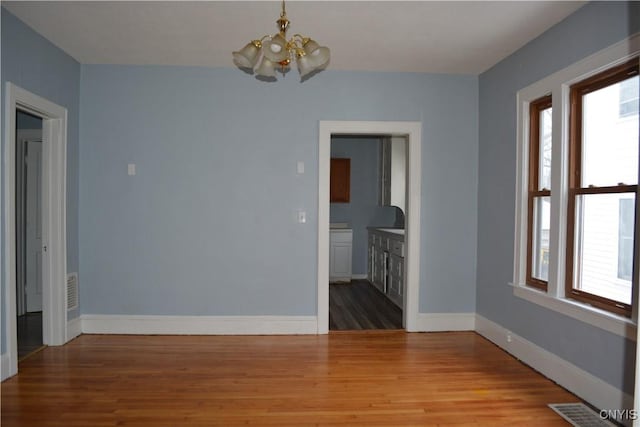 spare room with wood-type flooring and a chandelier