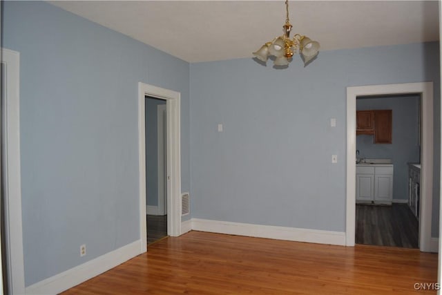 empty room featuring sink, hardwood / wood-style floors, and a notable chandelier