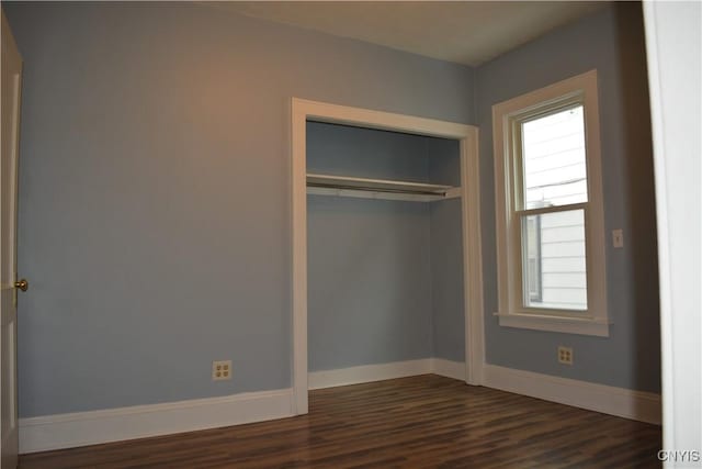 unfurnished bedroom featuring a closet and dark wood-type flooring