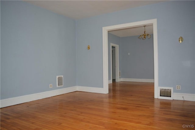 unfurnished room with hardwood / wood-style flooring and an inviting chandelier