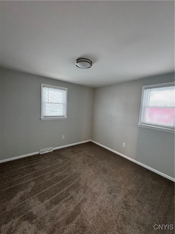 spare room featuring dark colored carpet