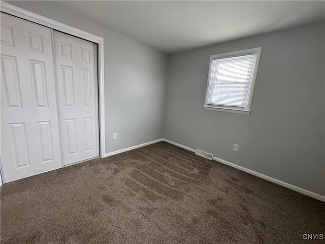 unfurnished bedroom featuring a closet and dark carpet