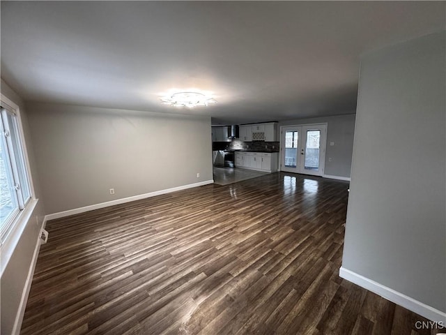 unfurnished living room featuring dark wood-type flooring, a wealth of natural light, and french doors