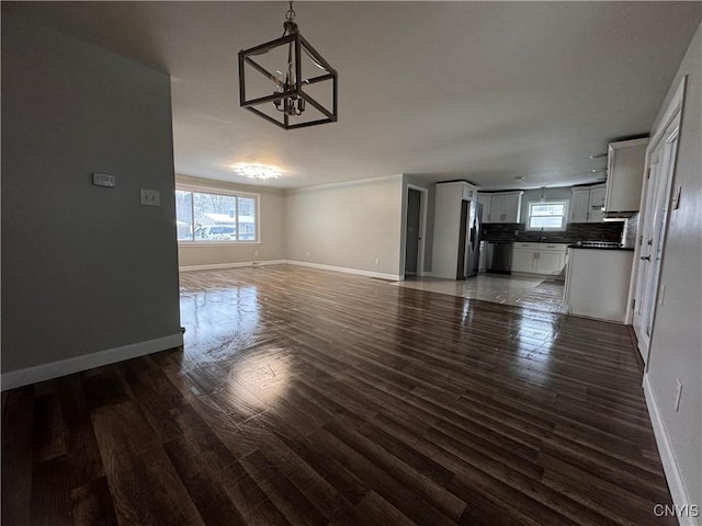 unfurnished living room featuring dark hardwood / wood-style flooring and a chandelier