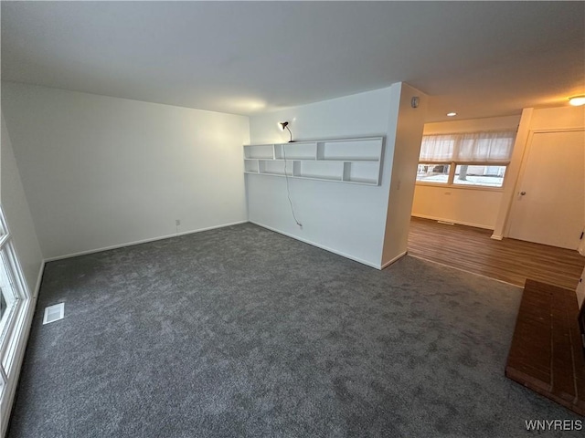 unfurnished living room with dark colored carpet