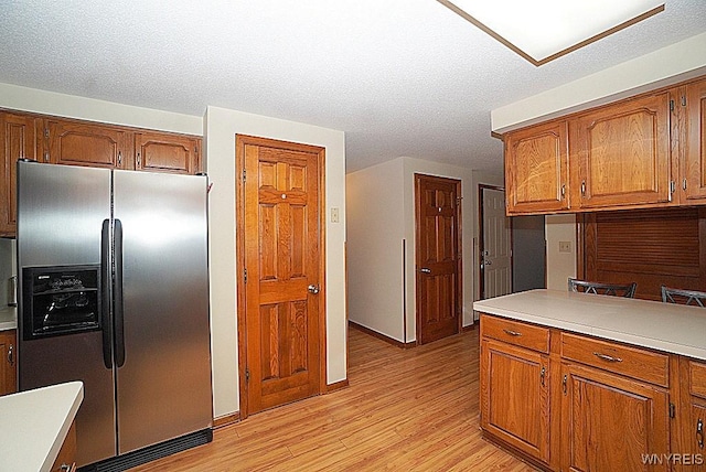 kitchen with stainless steel refrigerator with ice dispenser, a textured ceiling, and light hardwood / wood-style floors