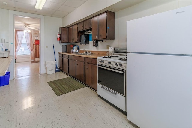 kitchen featuring stove, white refrigerator, sink, ceiling fan, and dark brown cabinets